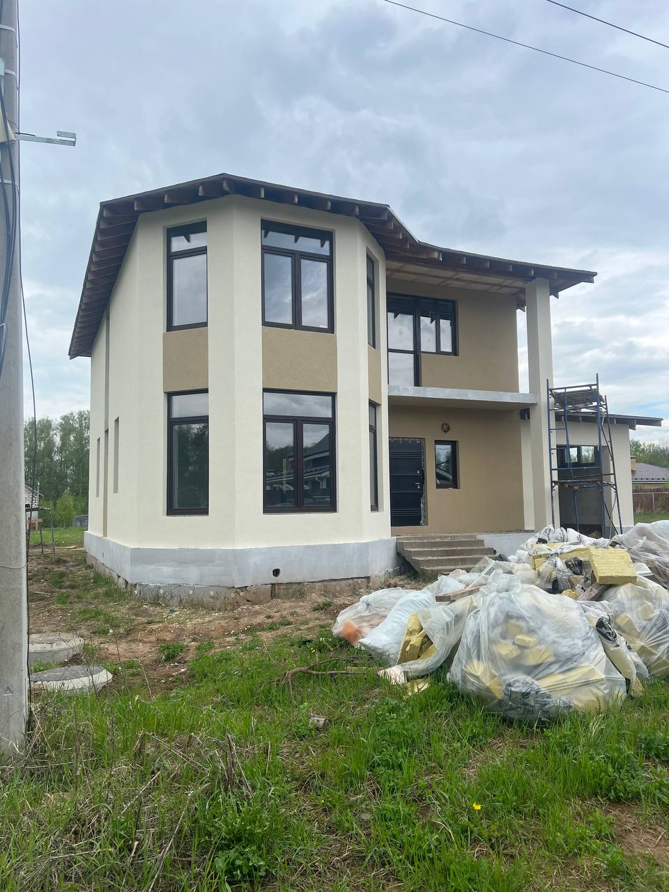 Дом с бежевой штукатуркой и тёмными окнами